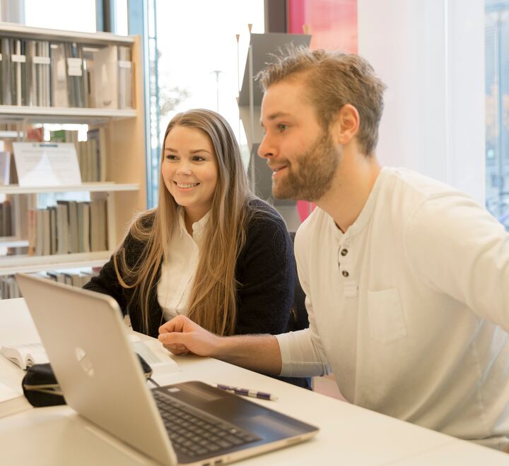 Studenter som sitter på å jobber på en pc, på et bibliotek